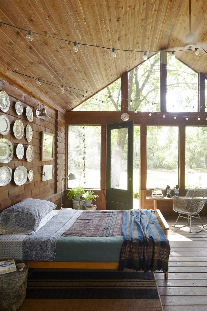 The screened porch’s collection of transferware plates was purchased at yard sales, the bedding is by John Robshaw, and the rocker is by Harry Bertoia; the walls are stained cedar. 