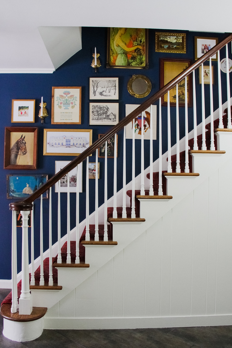 Benjamin Moore Washington Blue CW-630 stairwell wall with art and white stairs.
