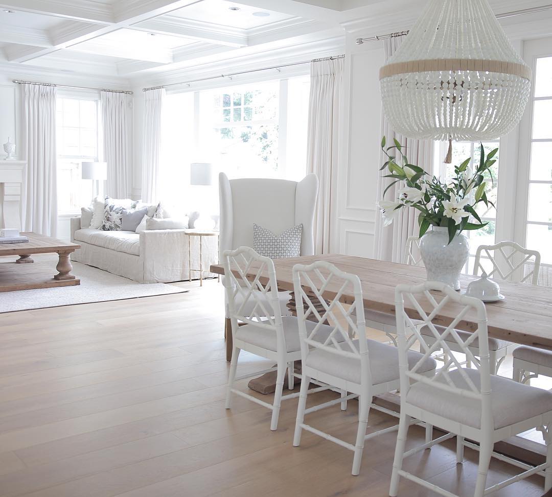 All white coastal styled interior with white walls, chairs, chandelier and sofa.