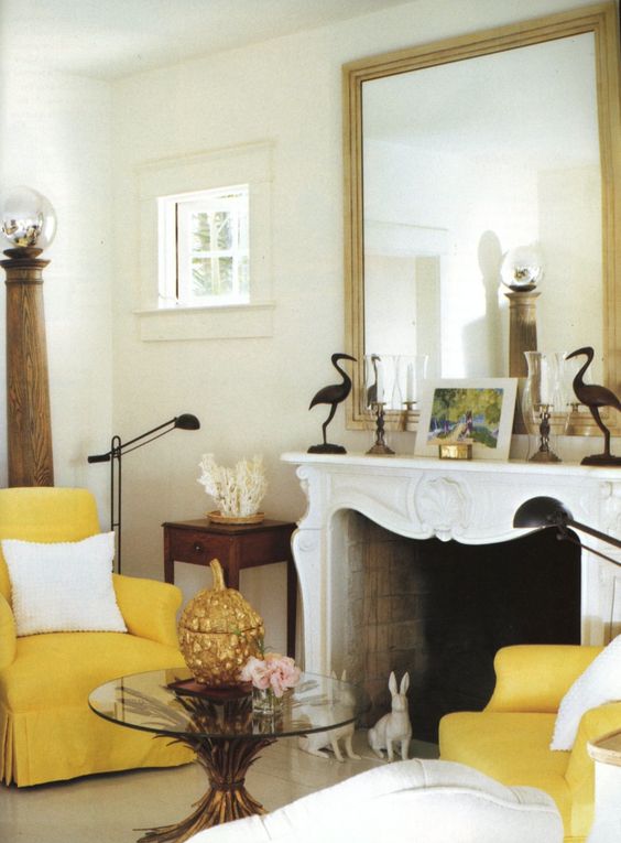Fireplace with mirror and two yellow armchairs.