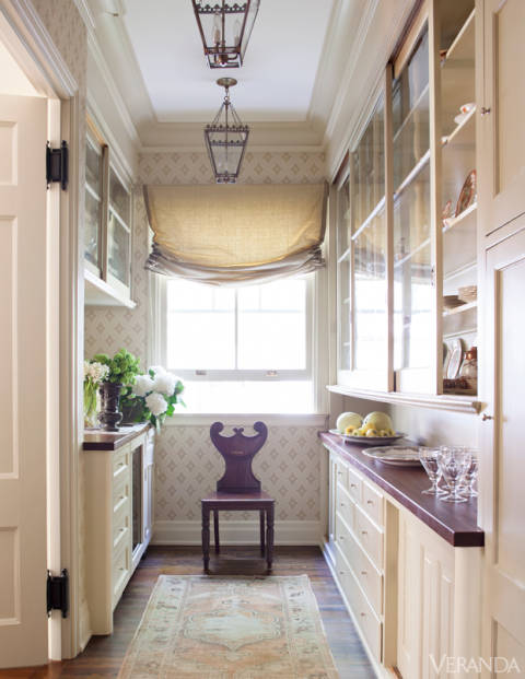 In fact, the renovation was so extensive that the famous pillars had to be taken down, and the house was propped up by trees until they were replaced. A staircase with the sweep of a hooped skirt was added, and the ceilings of the portico and side porch were painted sky blue, a 19th-century detail. Patterned Farrow & Ball wallpaper and an antique English hall chair dress up the butler's pantry. Roman shade in Rose Tarlow hemp-linen. Glassware, William Yeoward. Lanterns, Treillage.