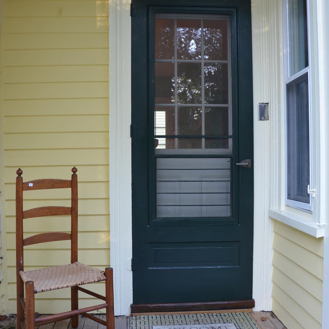 Back porch with door painted in Benjamin Moore Essex Green and walls in Hawthorne Yellow