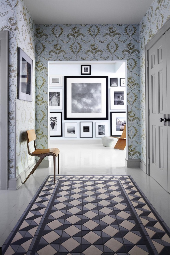 The entry hall features encaustic tiles inset into wood planks, the chair was found in a Dumpster, and the wallpaper is by Schumacher; the central photograph beyond is by Abranowicz, and the one to the right is by Horst. 