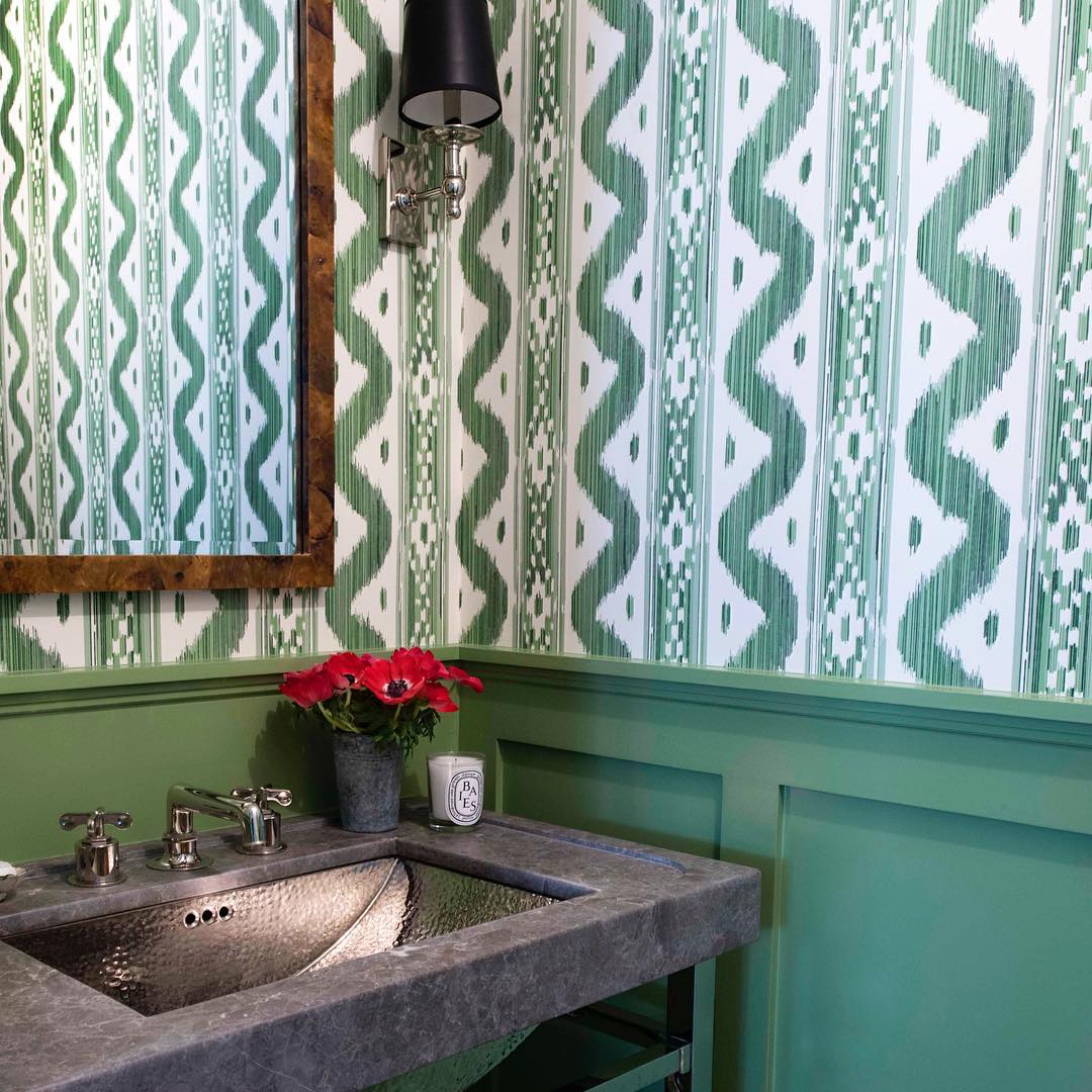 Green color scheme for this bathroom with green painted wainscoting and green and white wallpaper.