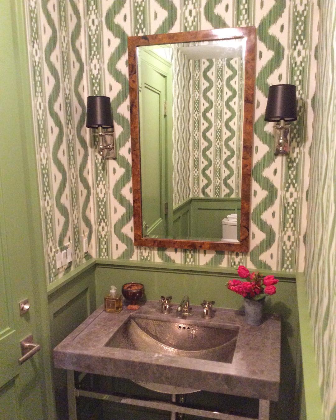Green color scheme for this bathroom with green painted wainscoting and green and white wallpaper.