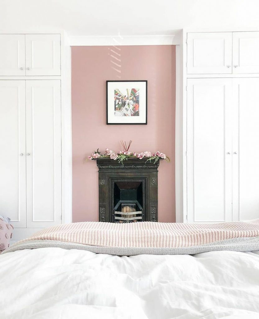 Farrow & Ball Sulking Room Pink feature wall bedroom with crisp white cupboards. Fresh linen and fireplace