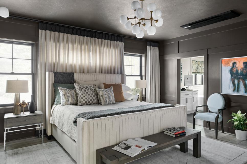 Mixing creamy tones from the upholstered pinstriped bed frame to the soft layers of bedding creates an inviting focal point.