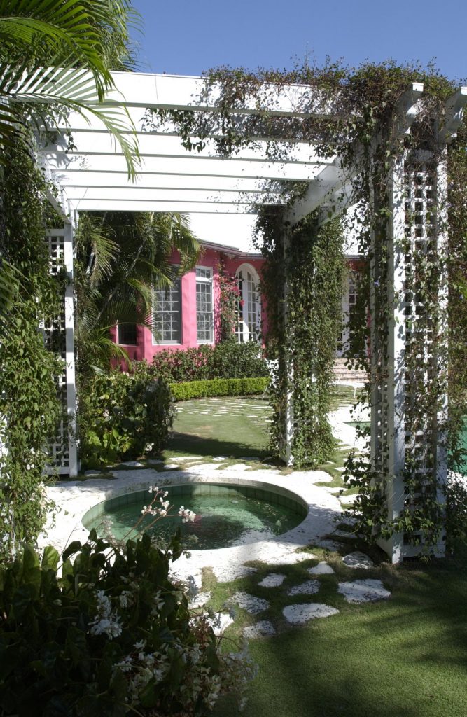 White pergola over a small round fountain