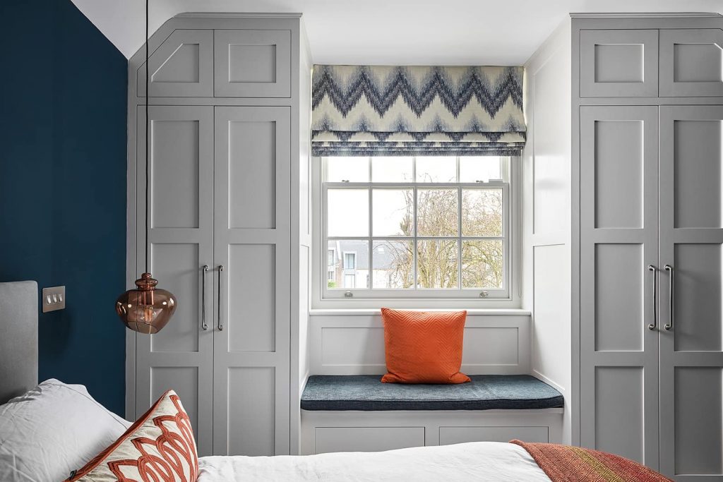 Bedroom Walls Painted in Farrow and Ball Ammonite. Blue and orange color scheme interior, window seat