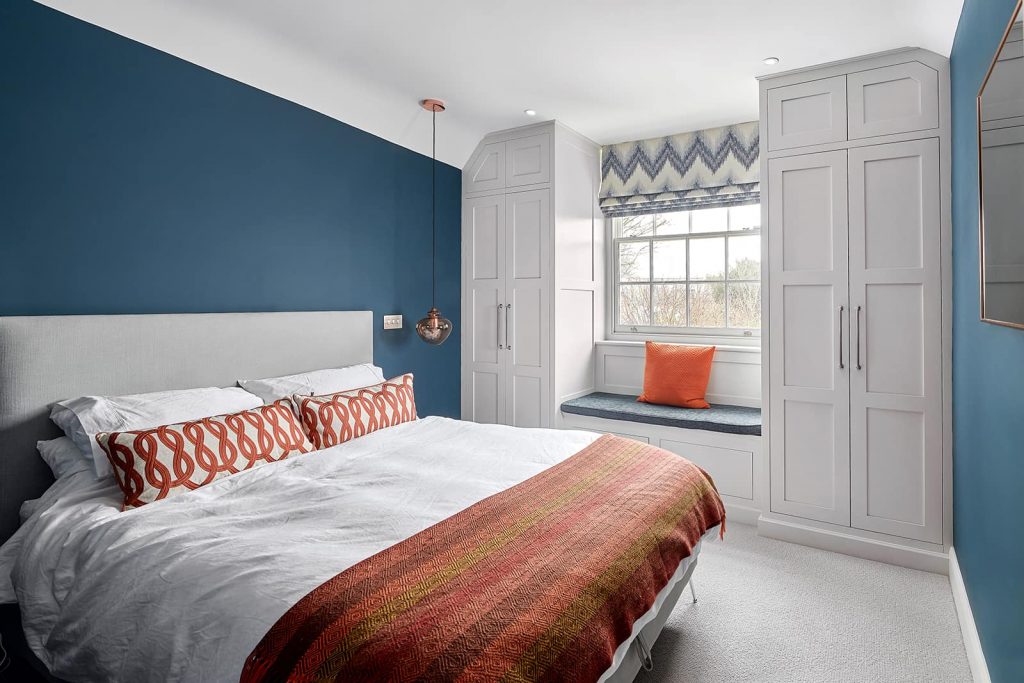 Bedroom Walls Painted in Farrow and Ball Ammonite. Blue and orange color scheme interior