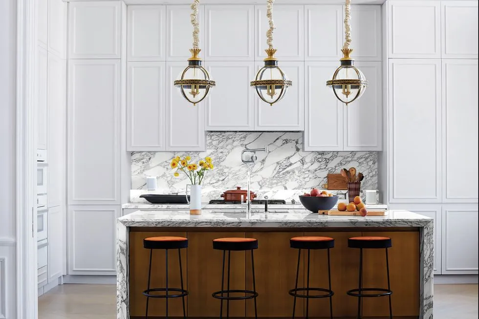 An all white kitchen with with marble waterfall island and marble splash back.
