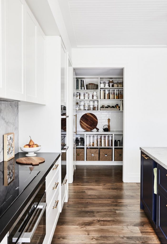 he grey tones of the benchtop contrast with the organic brass tapware and the indigo joinery