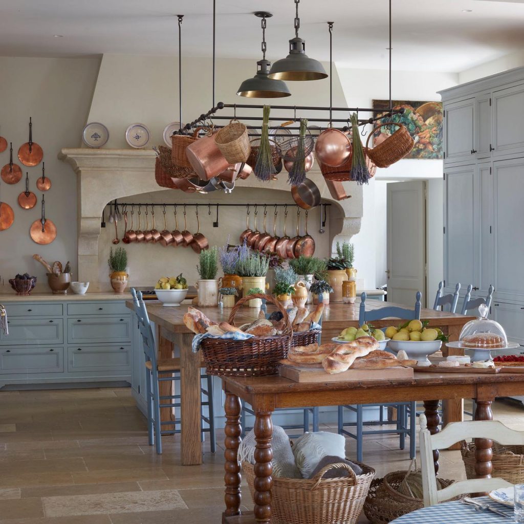 Country kitchen with light blue painted cabinets and hanging copper pots